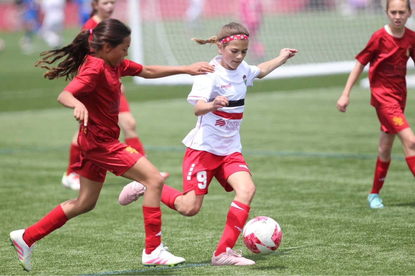 A St. Louis Legends player in a white kit attacks the ball against red-shirted opponents